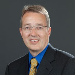 Headshot of Dr. Gampper wearing a dark suit and light necktie