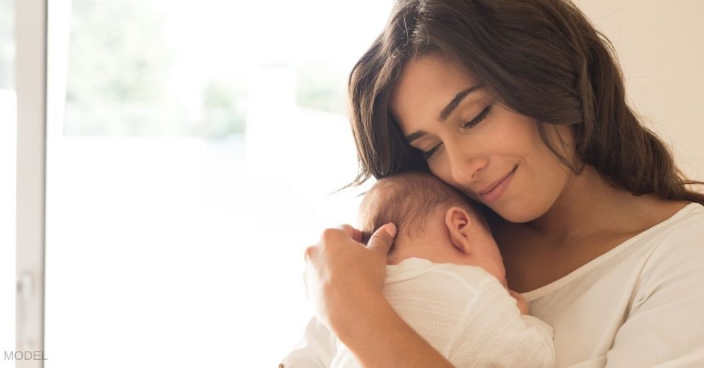 Beautiful woman holding a swaddled baby. (MODELS)