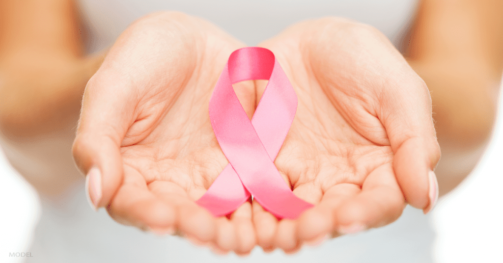 Closeup of outstretched hands with a pink breast cancer awareness ribbon in the palms