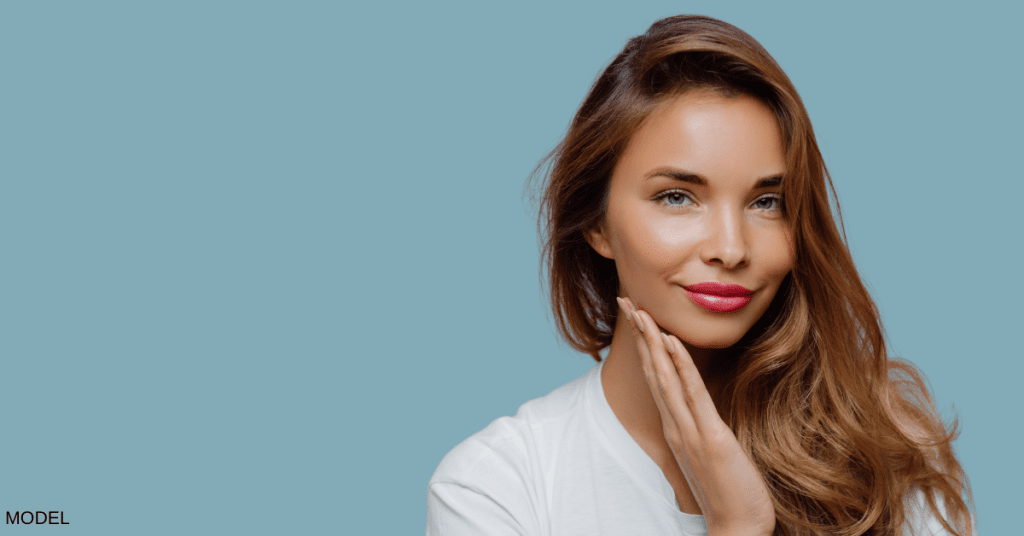 Woman smiling while touching her chin (model)