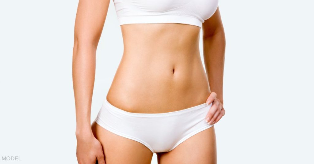Woman in white undergarments with hand on hip. (MODEL)