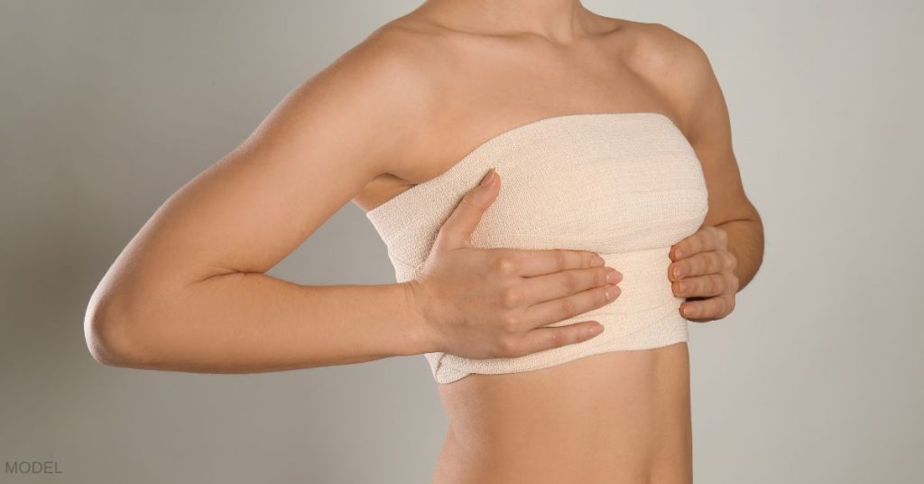 Woman holding her hands on the bandages around her bust. (MODEL)